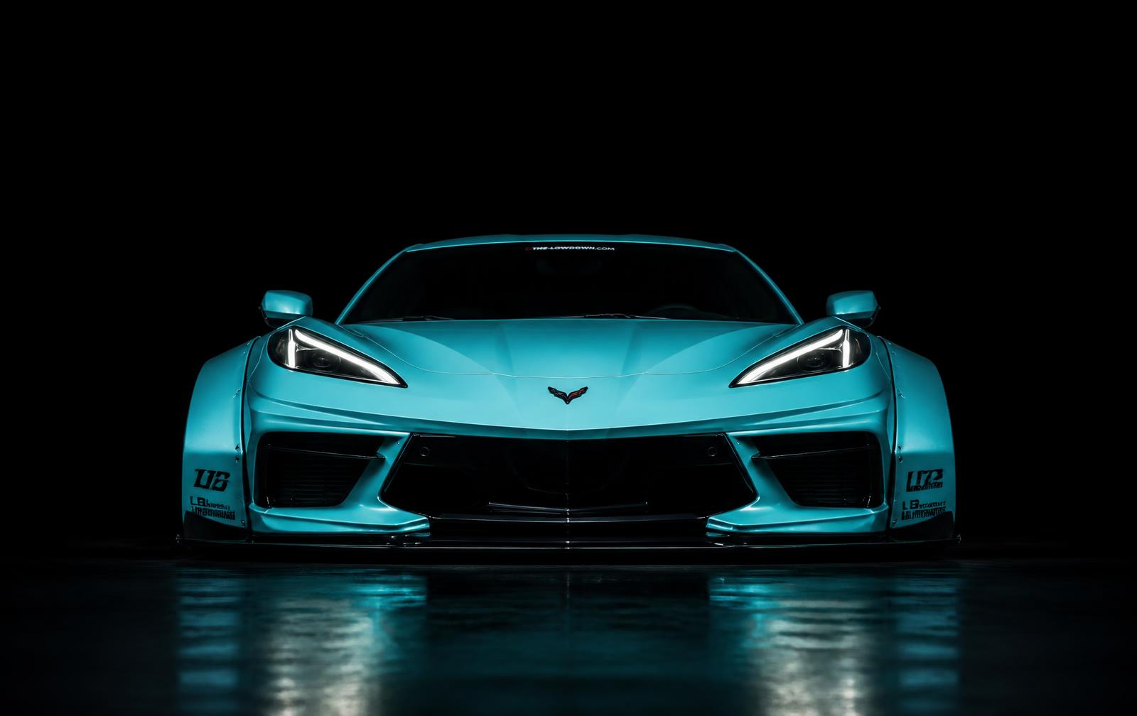 Straight-on low-angle front shot of the Tiffany-blue widebody C8 Corvette in a black environment
