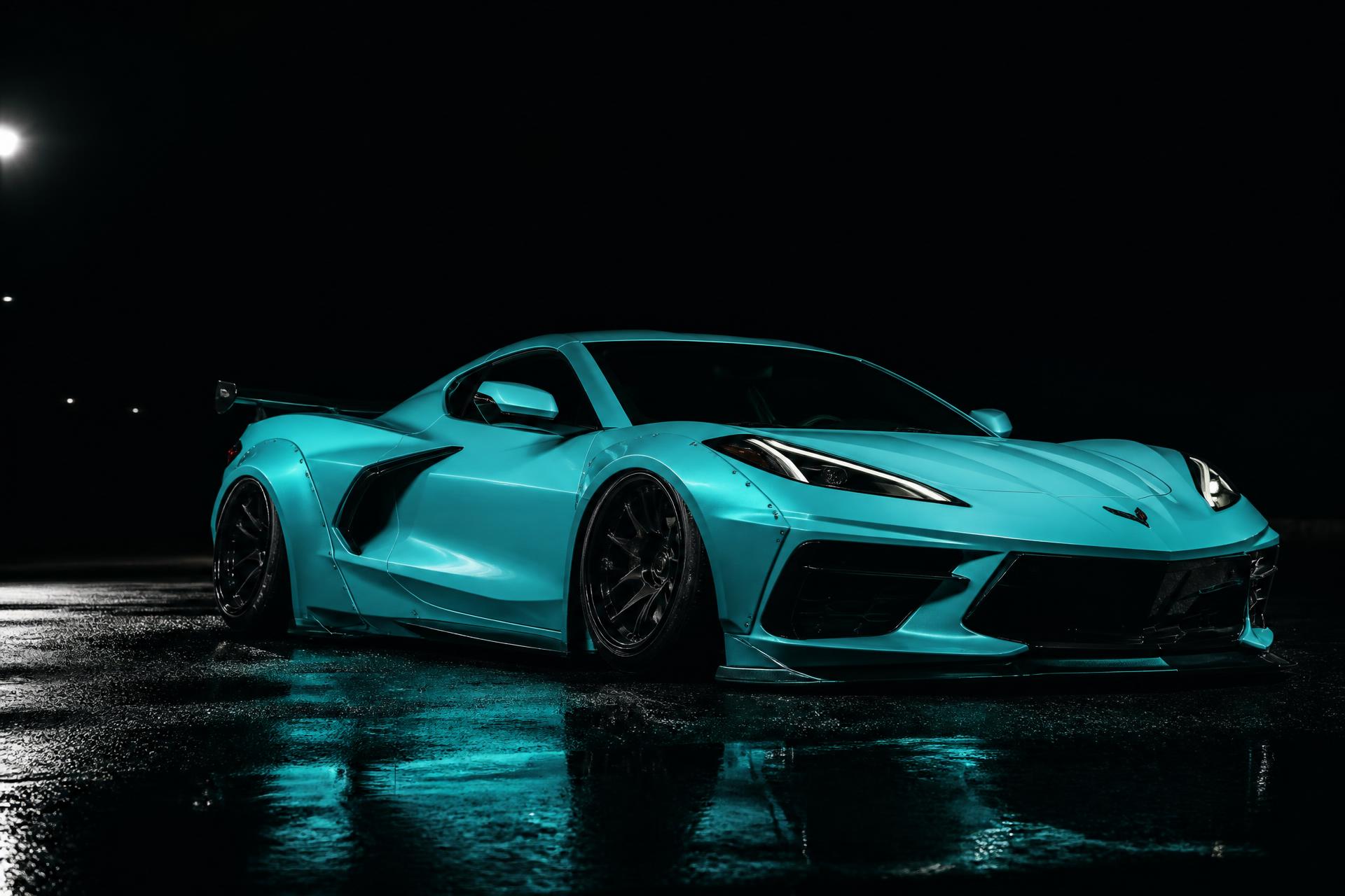 Tiffany-blue widebody C8 Corvette lit dramatically at night on wet asphalt